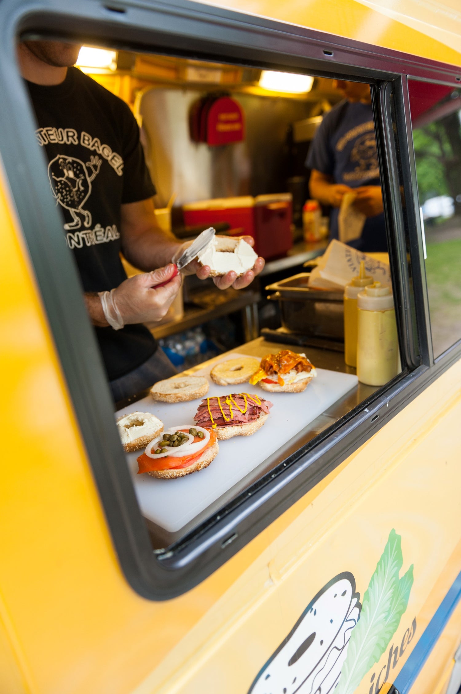 Inside the St-Viateur Bagel truck, someone preparing bagel sandwhiches.