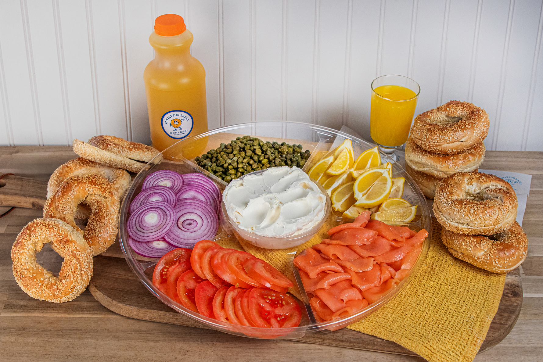 Bagels and catering platter with cream cheese, smoked salmon, tomatoes, onions, capers, and lemons, plus freshly-squeezed orange juice.