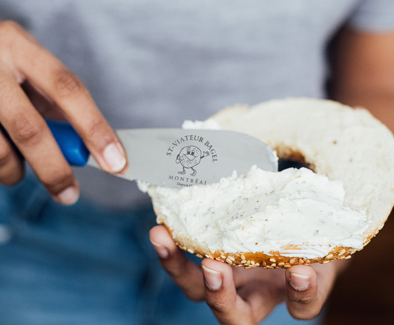 Spreading knife with logo being used to put cream cheese on a St-Viateur bagel.