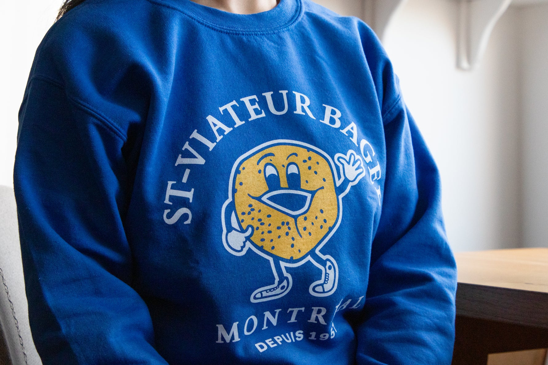 Person wearing a blue crewneck sweater with the iconic St-Viateur logo.