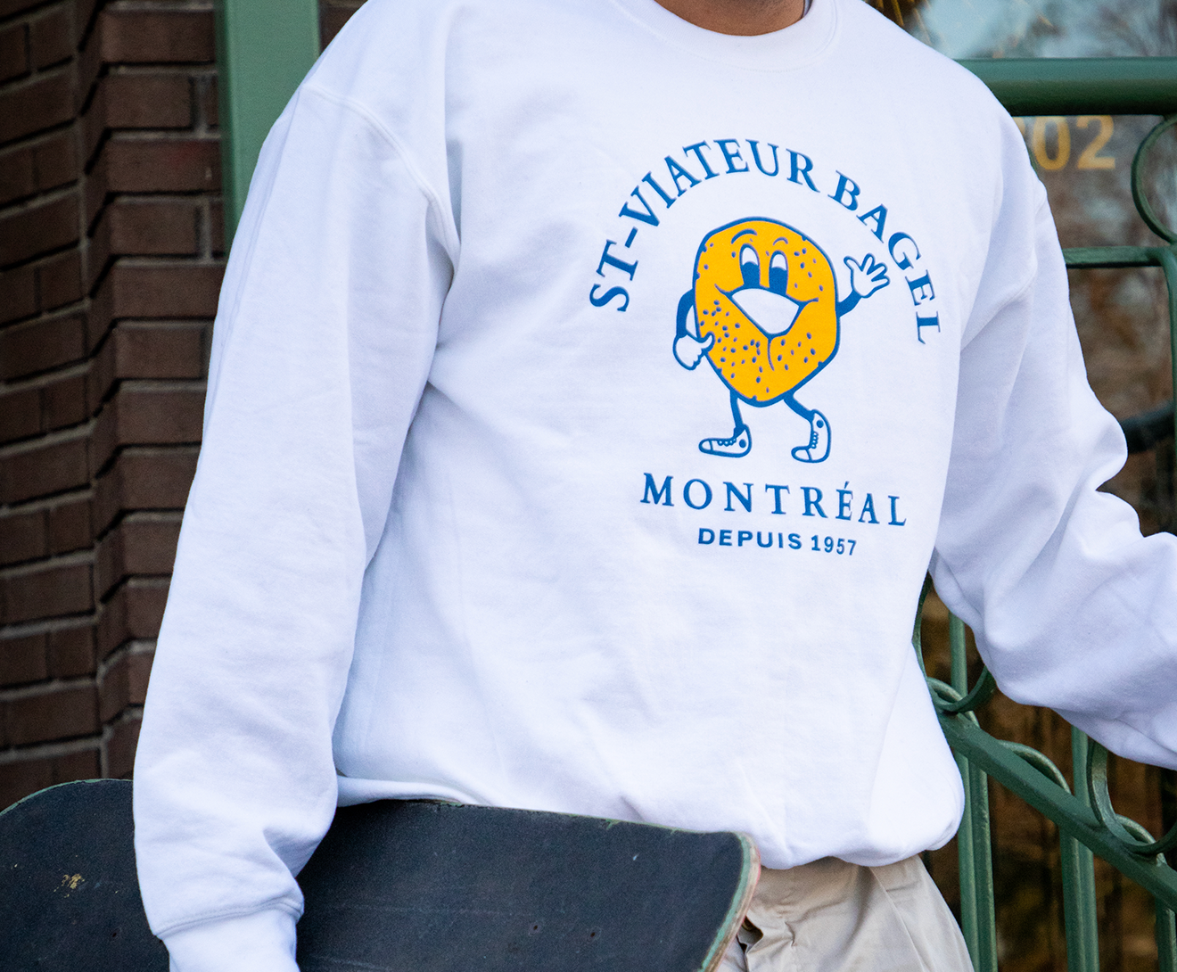 Person wearing a white crewneck sweater with the iconic St-Viateur logo.